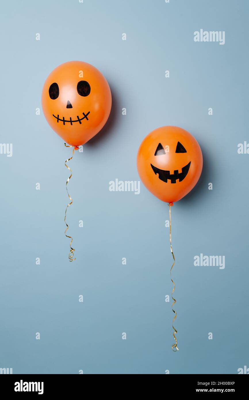 Palloncini d'arancia di Halloween con grimaces ispirati alla zucca intagliata. Su sfondo blu. Foto Stock