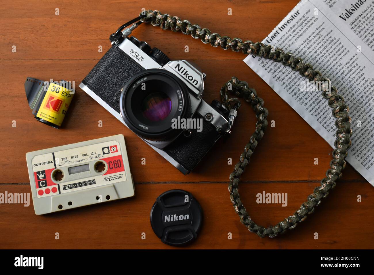 Fotocamera Nikon FM2 e altri oggetti analogici su un tavolo di legno. Foto Stock