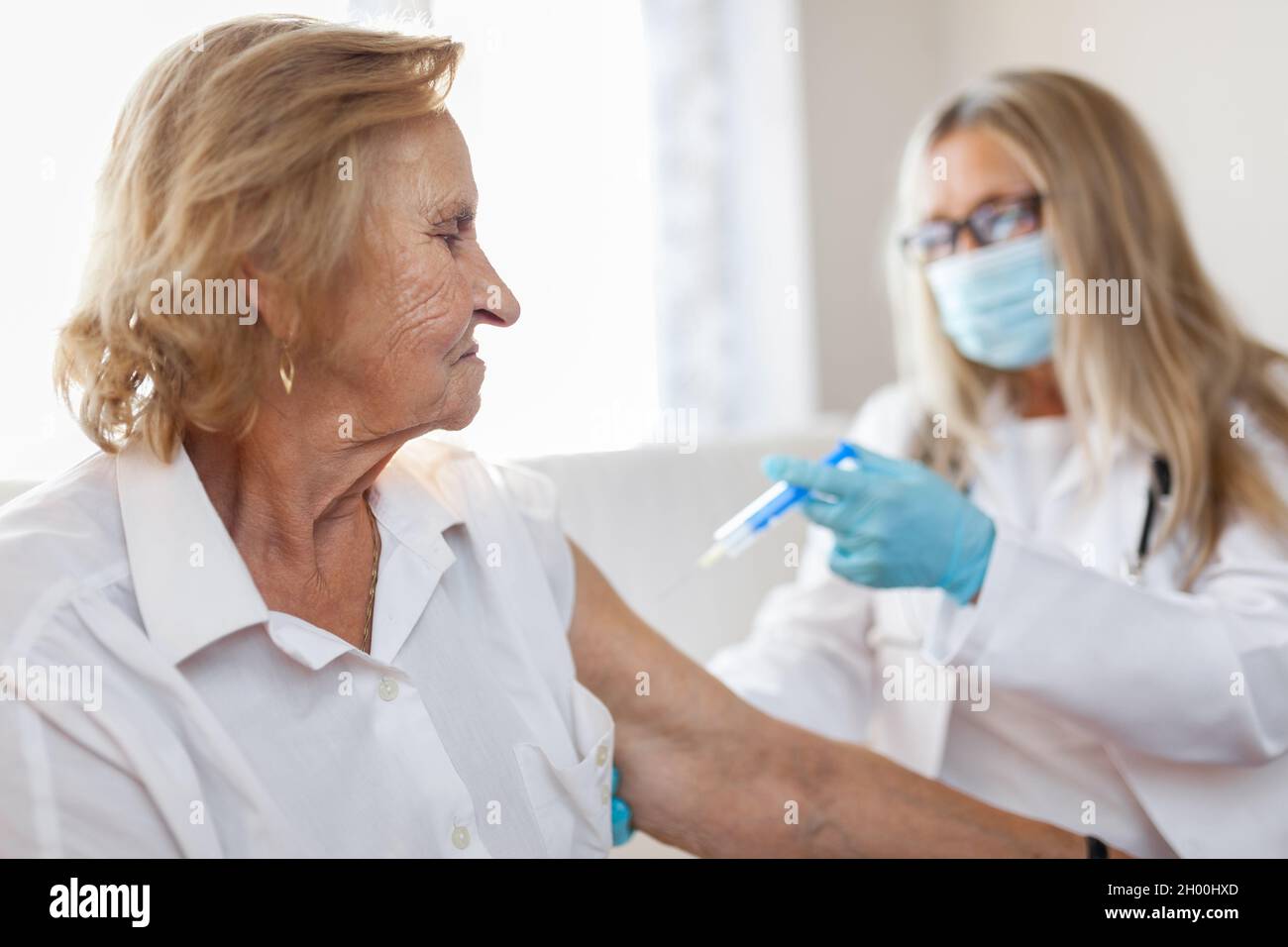 Medico la somministrazione di un vaccino su un paziente anziano Foto Stock