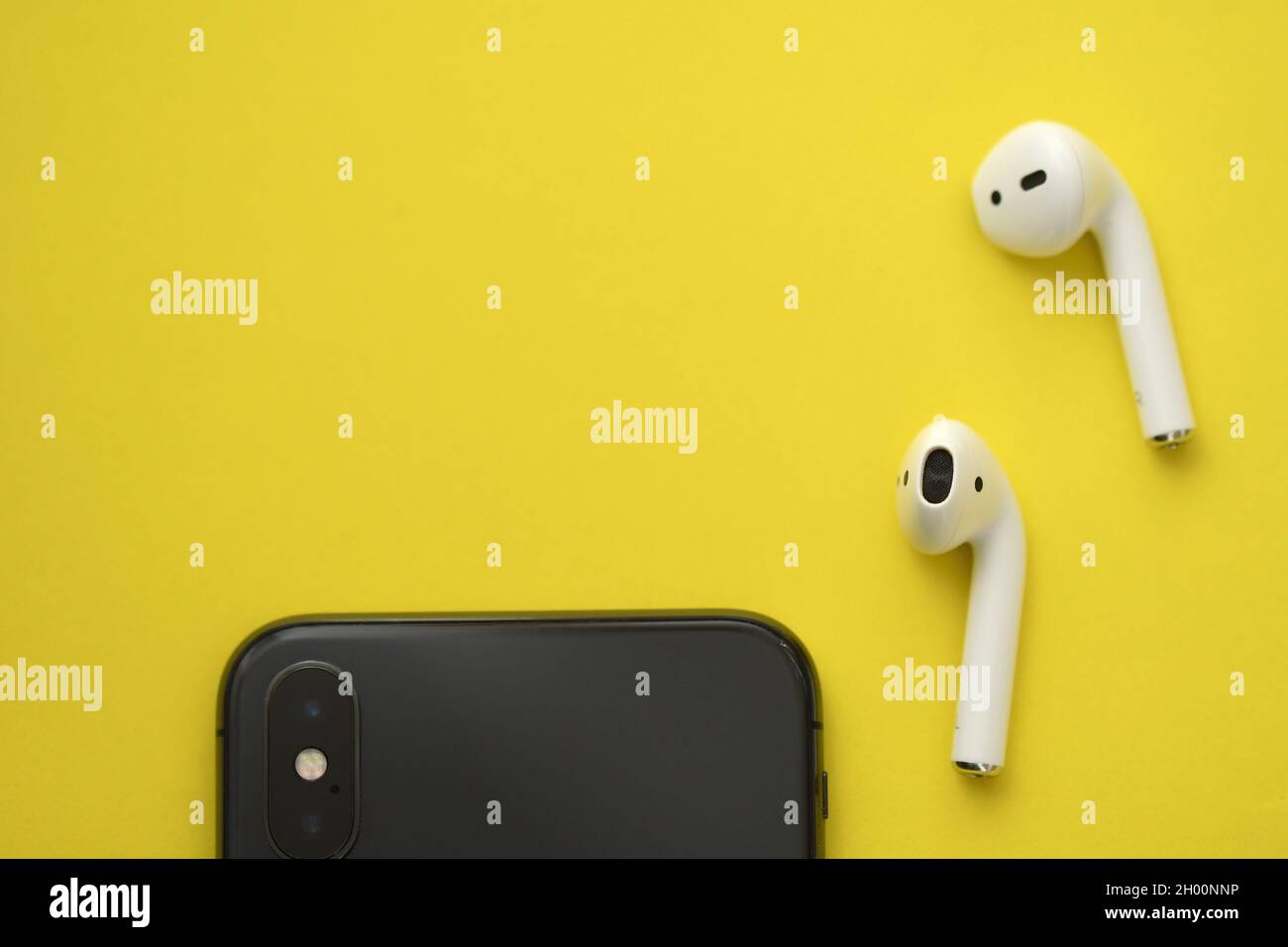 Overhead di un telefono cellulare e auricolari wireless su sfondo giallo Foto Stock