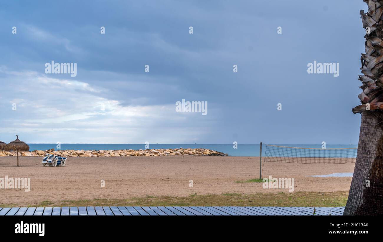 Vista della spiaggia deserta presto al mattino con nuvole tempesta lontane Foto Stock