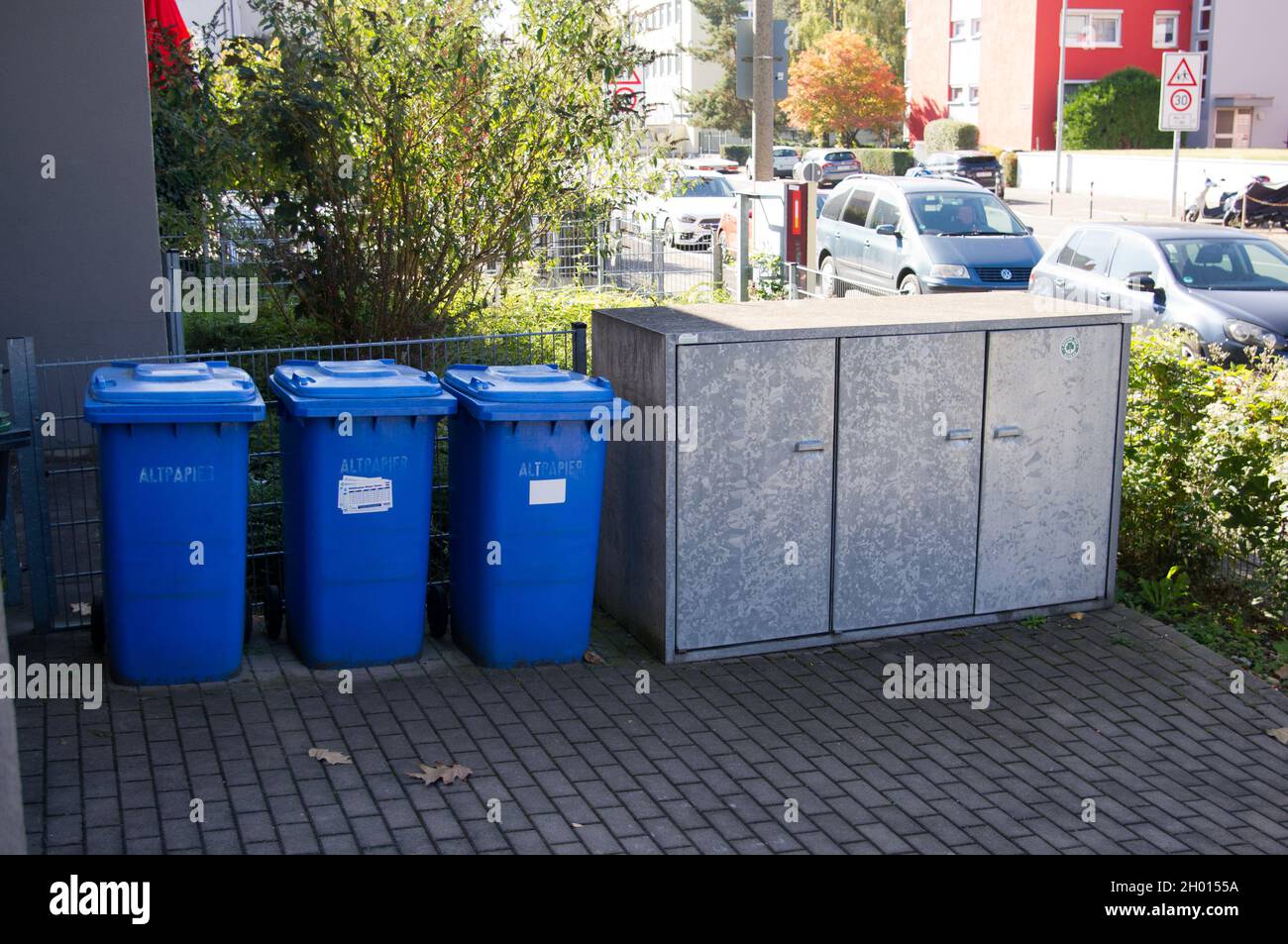 contenitori blu per la raccolta della carta di scarto accanto a un contenitore per contenitori per rifiuti residui Foto Stock