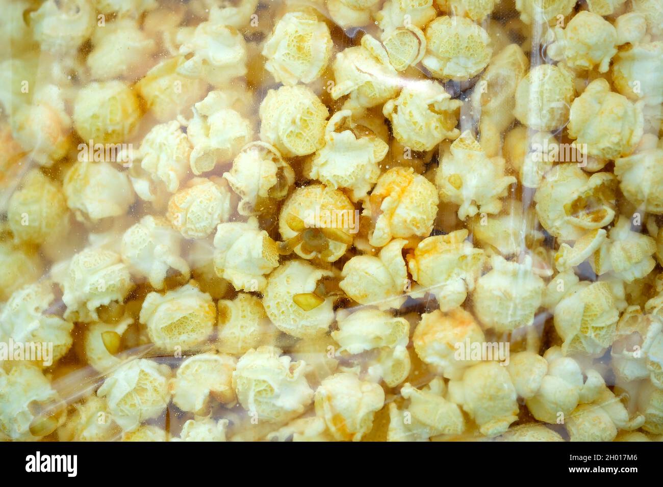 Confezionamento popcorn salato con sapore di formaggio sacchetto di plastica trasparente vista dall'alto. Granaglie di mais dall'Argentina che stanno schioccando aperto. Grandi grani di popcor Foto Stock