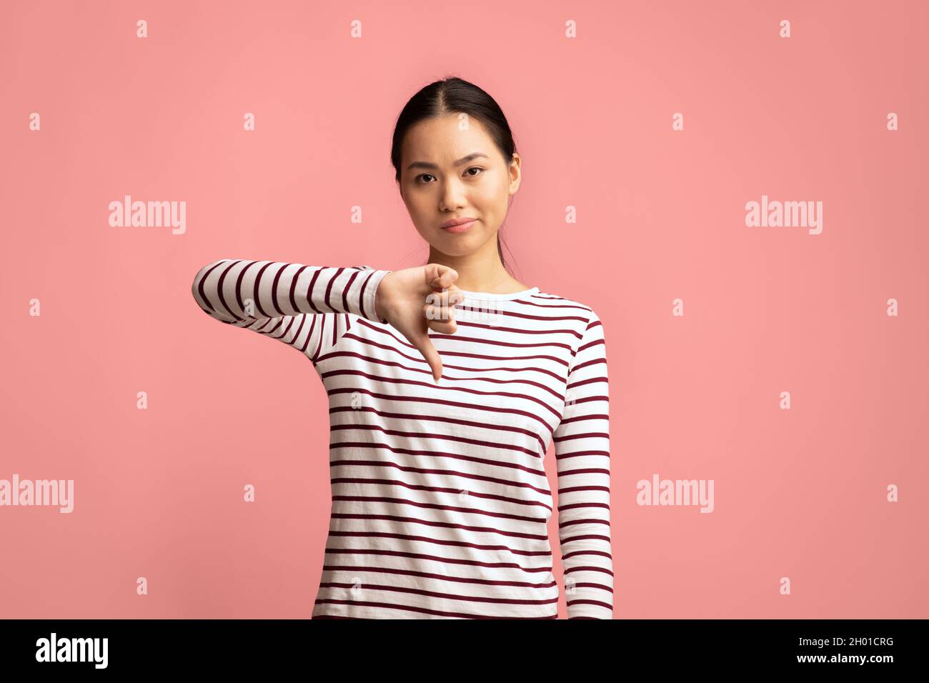 Non mi piace. Deluso Asian Female che mostra Thumb Down Gesture a Camera, infelice giovane coreana donna che esprime disapprovazione con espressione media del volto, Foto Stock