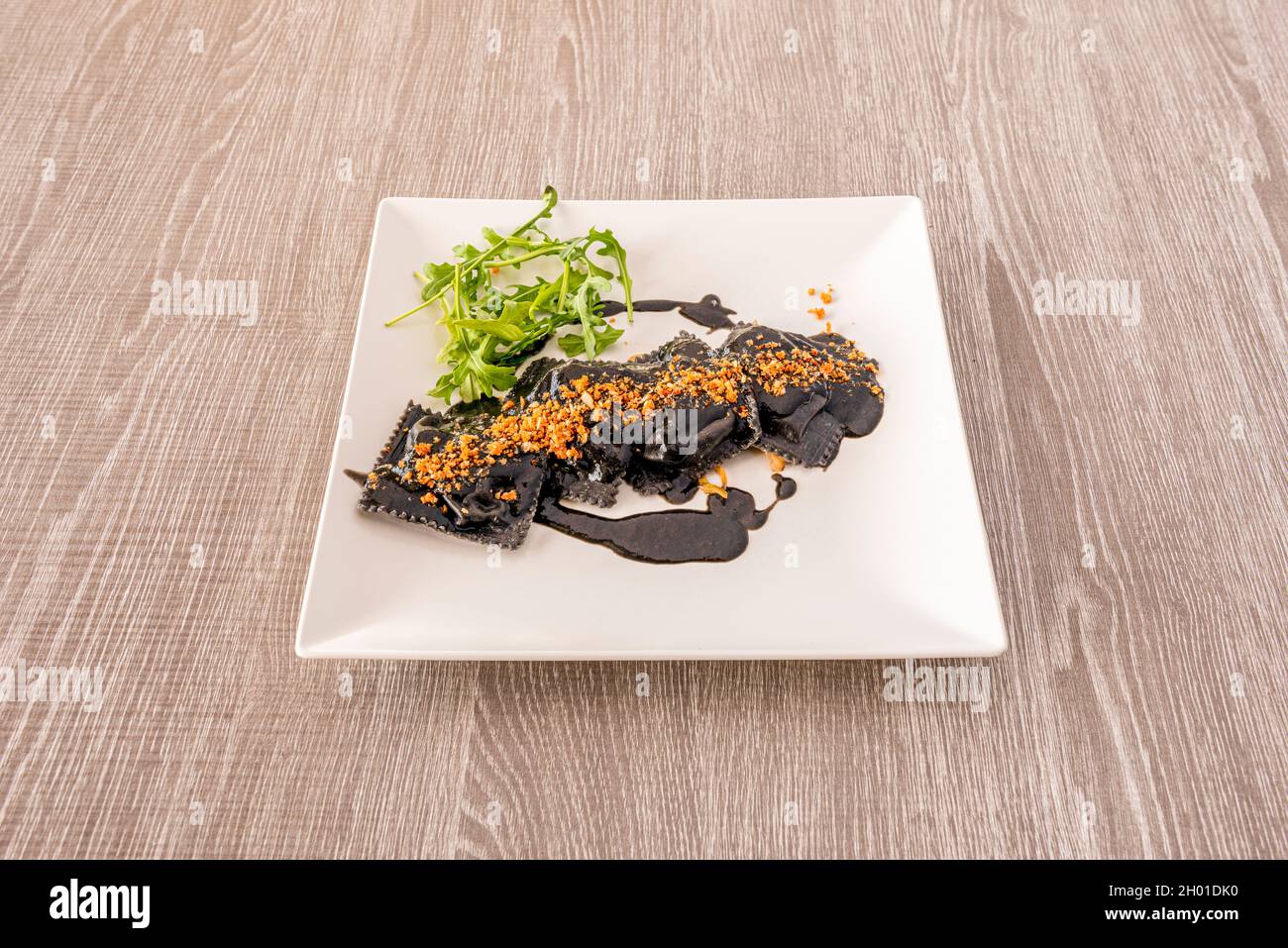 Ravioli ripieni di pesce con salsa di inchiostro calamaro e rucola Foto Stock