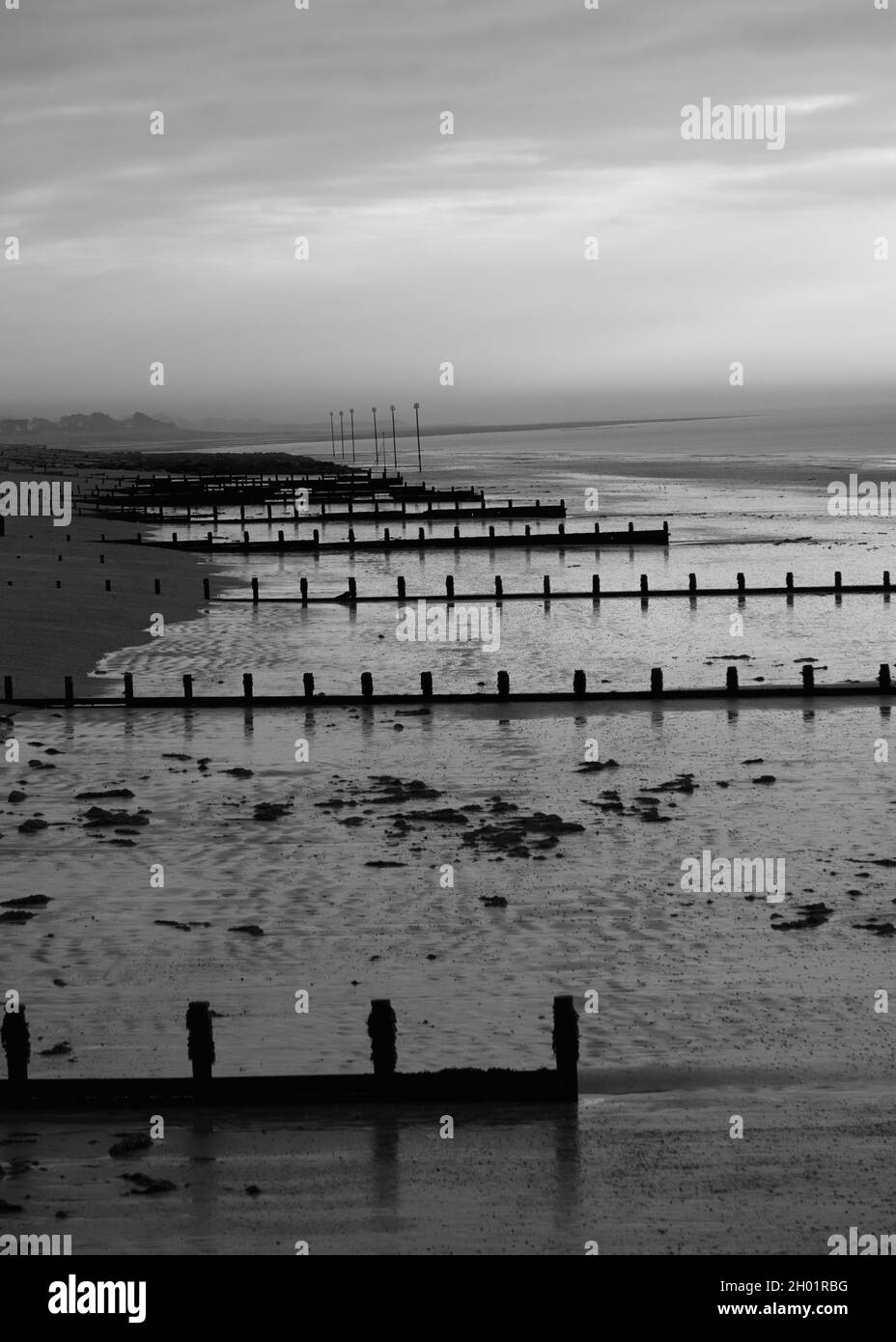 Immagine bianca e nera di groynes di legno che serve come seadefenses sulla spiaggia di Bognor Regis. Foto Stock