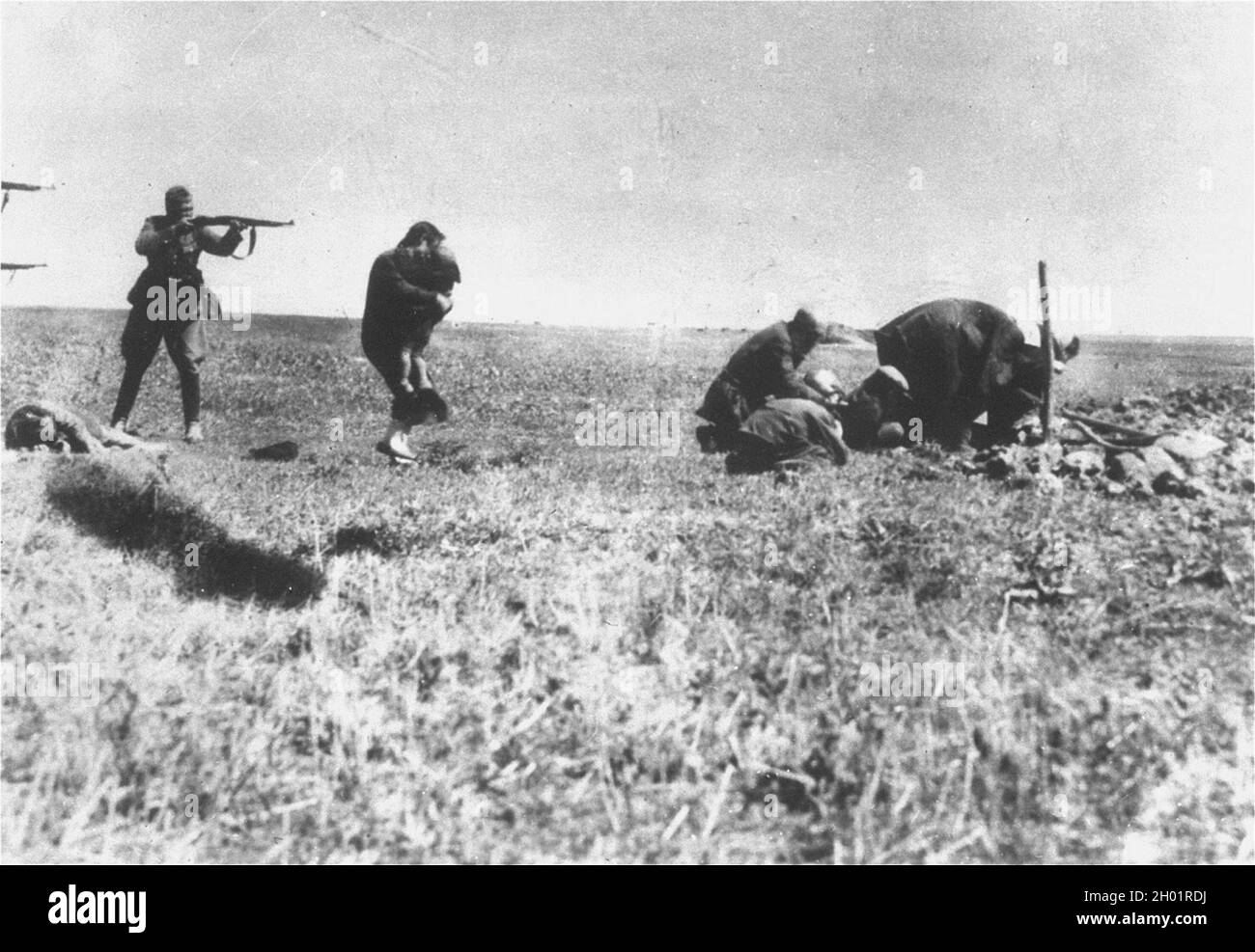 Un membro dell'Einsatgruppen (le SS naziste distaccate con il compito di distruggere gli ebrei in URSS) si prepara a sparare e a tenere la madre il suo bambino. Foto Stock