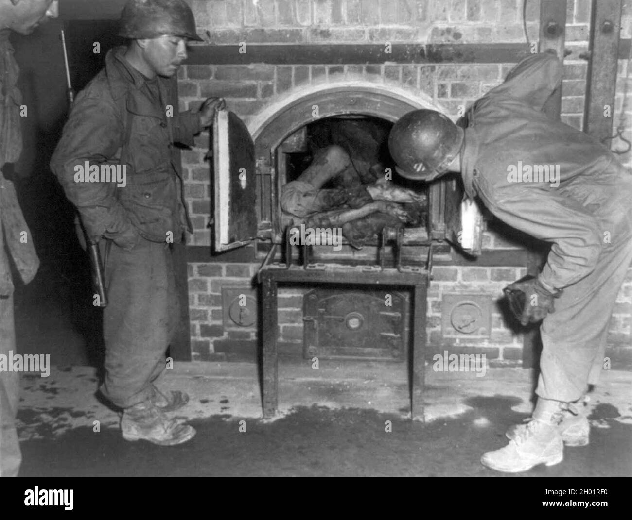 Tre soldati degli Stati Uniti guardano i corpi imbalsamati in un forno in un crematorio nell'aprile del 1945. Campo di concentramento di Dachau. Foto Stock
