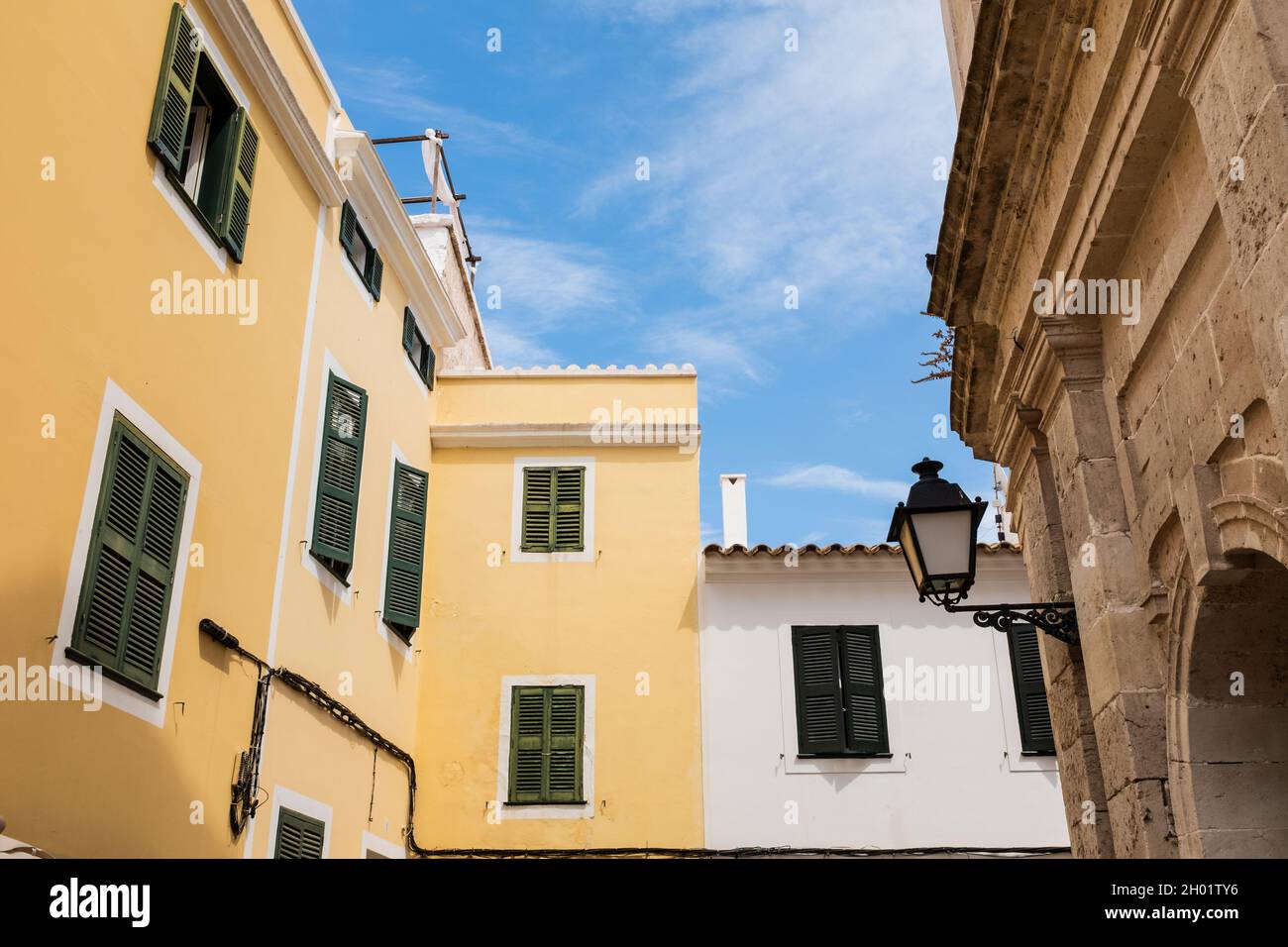 Case bianche e gialle facciate con finestre in legno verde chiuso a Ciutadella Menorca Foto Stock