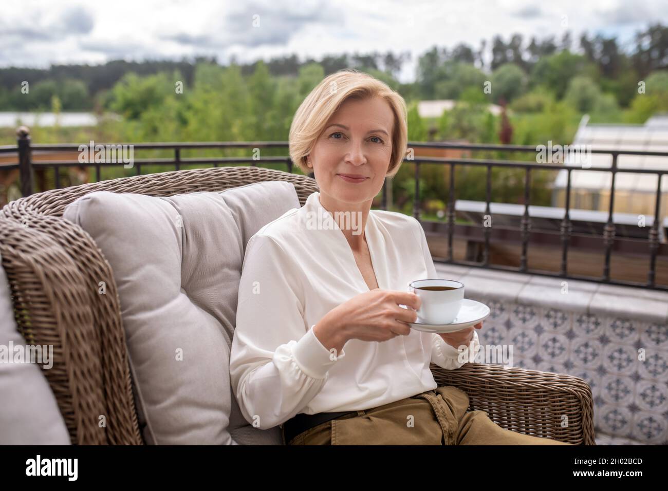 Calma elegante bionda donna bere caffè all'aperto Foto Stock