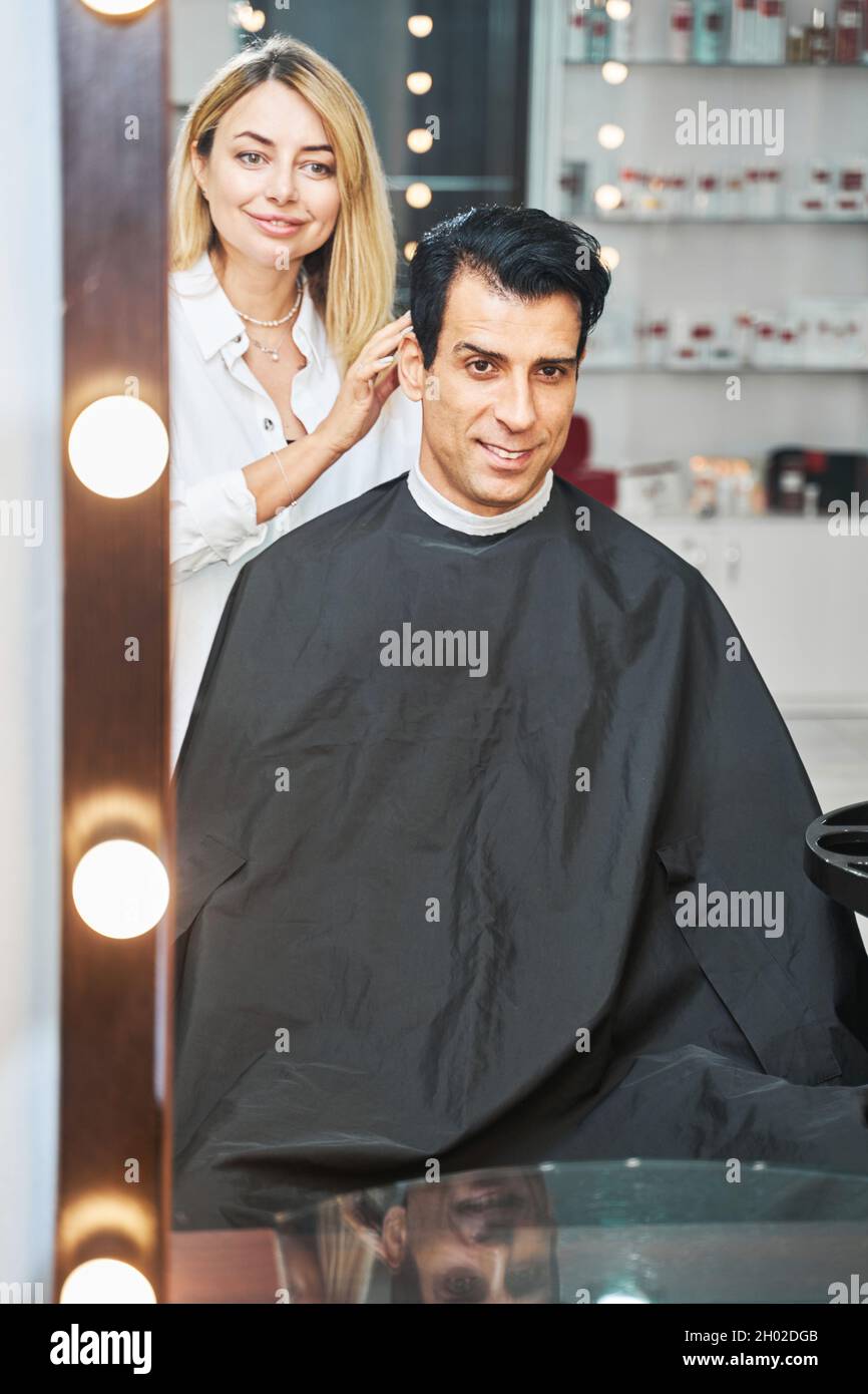 Donna barbiere che controlla la lunghezza dei capelli del visitatore Foto Stock