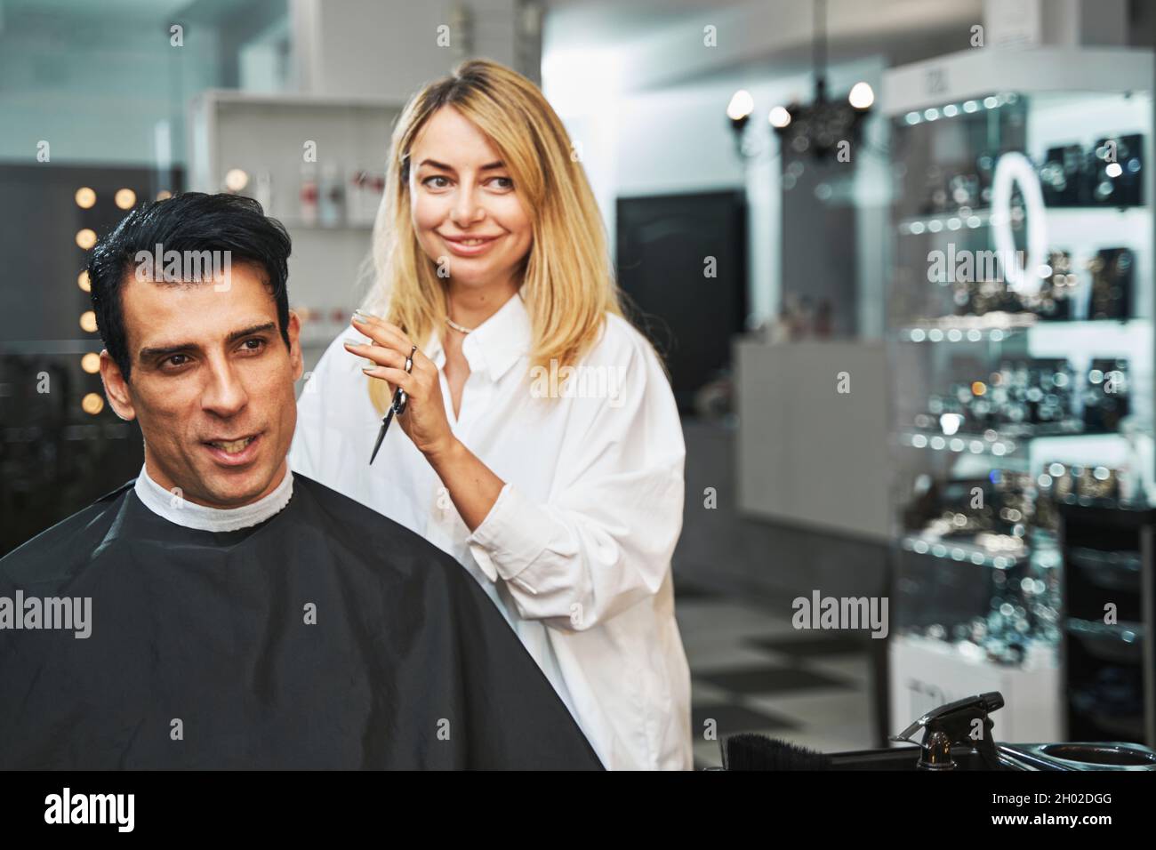 Maschio visitatore che dice al barbiere che taglio di capelli vuole Foto Stock