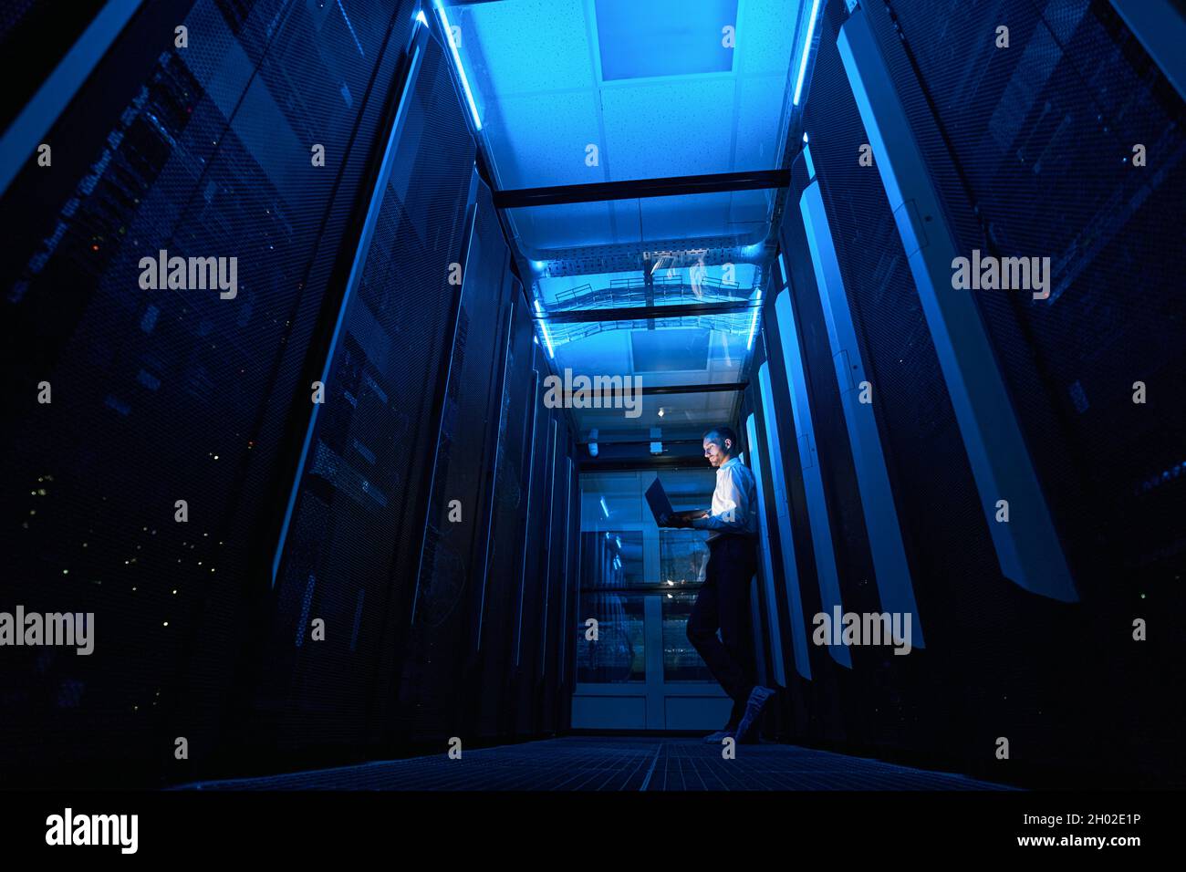 Tecnico del server che lavora con il laptop nella passerella della struttura dati Foto Stock