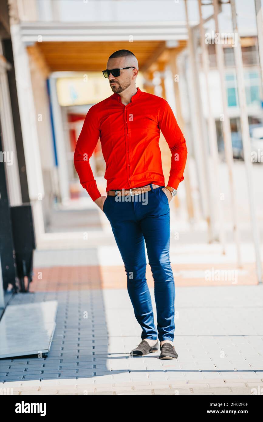 Bell'uomo caucasico che indossa un'elegante camicia rossa e occhiali da  sole in posa all'aperto Foto stock - Alamy