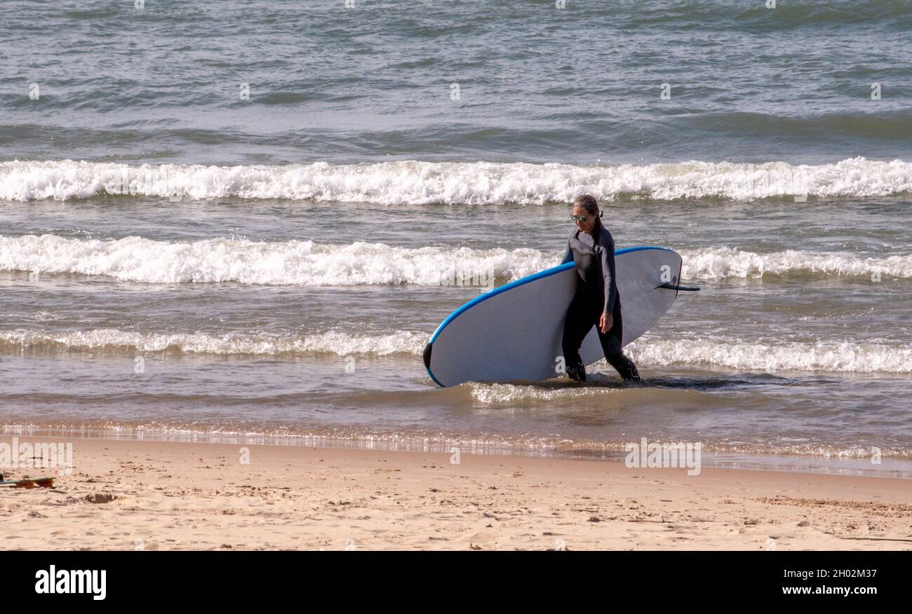 St Joseph MI USA, 26 settembre 2021; una donna in costume da bagno uscì da un lago Michigan freddo, con la sua tavola da surf Foto Stock