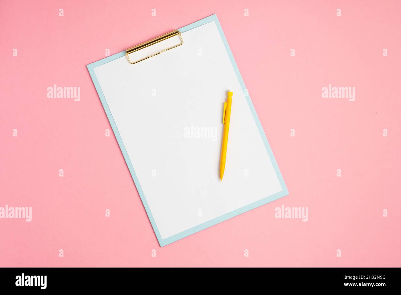 Area di lavoro rosa con lavagna a clip vuota e matita Foto Stock