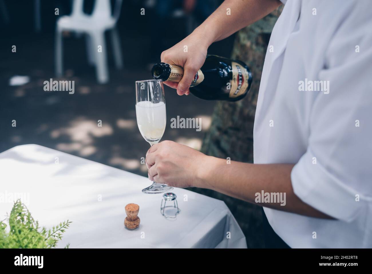 NORALA, PH– 22 SETTEMBRE 2021: Primo piano di mani versare la bottiglia di vino frizzante Martini in un alto vitigno. Messa a fuoco selettiva. Spazio di copia. Foto Stock