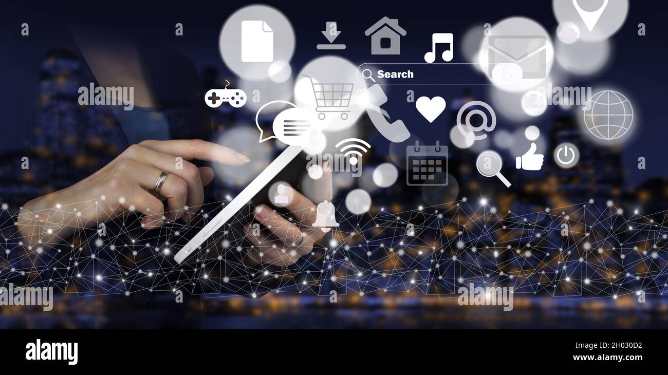 Comunicazione e concetto di rete. Tablet bianco con tocco a mano e ologramma digitale, le icone dei social media si illuminano su sfondo sfocato scuro della città. Onli digitali Foto Stock