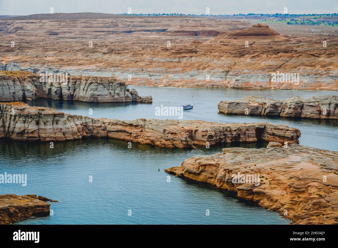 Lungo litorale con rocce rosse e scogliere, e houseboat sul lago Powell nello Utah Foto Stock