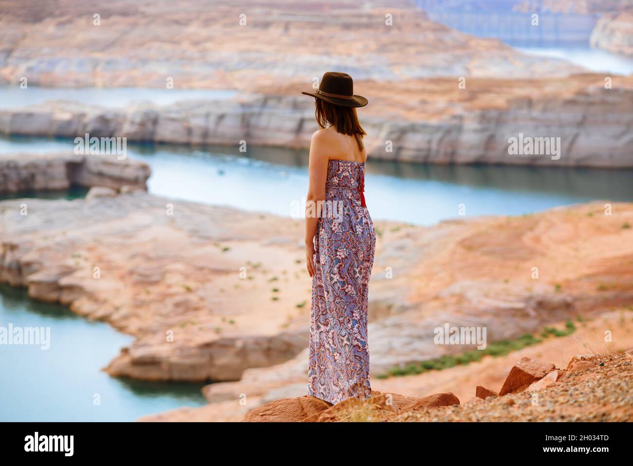 Donna in estate vestito indossare un cappello sulla spiaggia che si affaccia sul lago Powell, vista posteriore Foto Stock