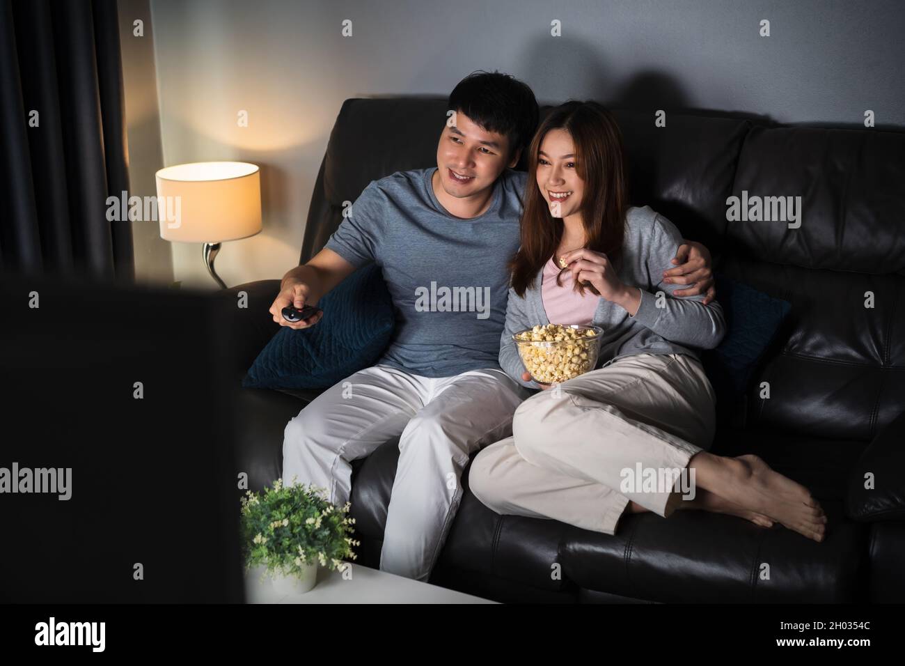 Felice coppia giovane che guarda la TV sul divano di notte Foto Stock