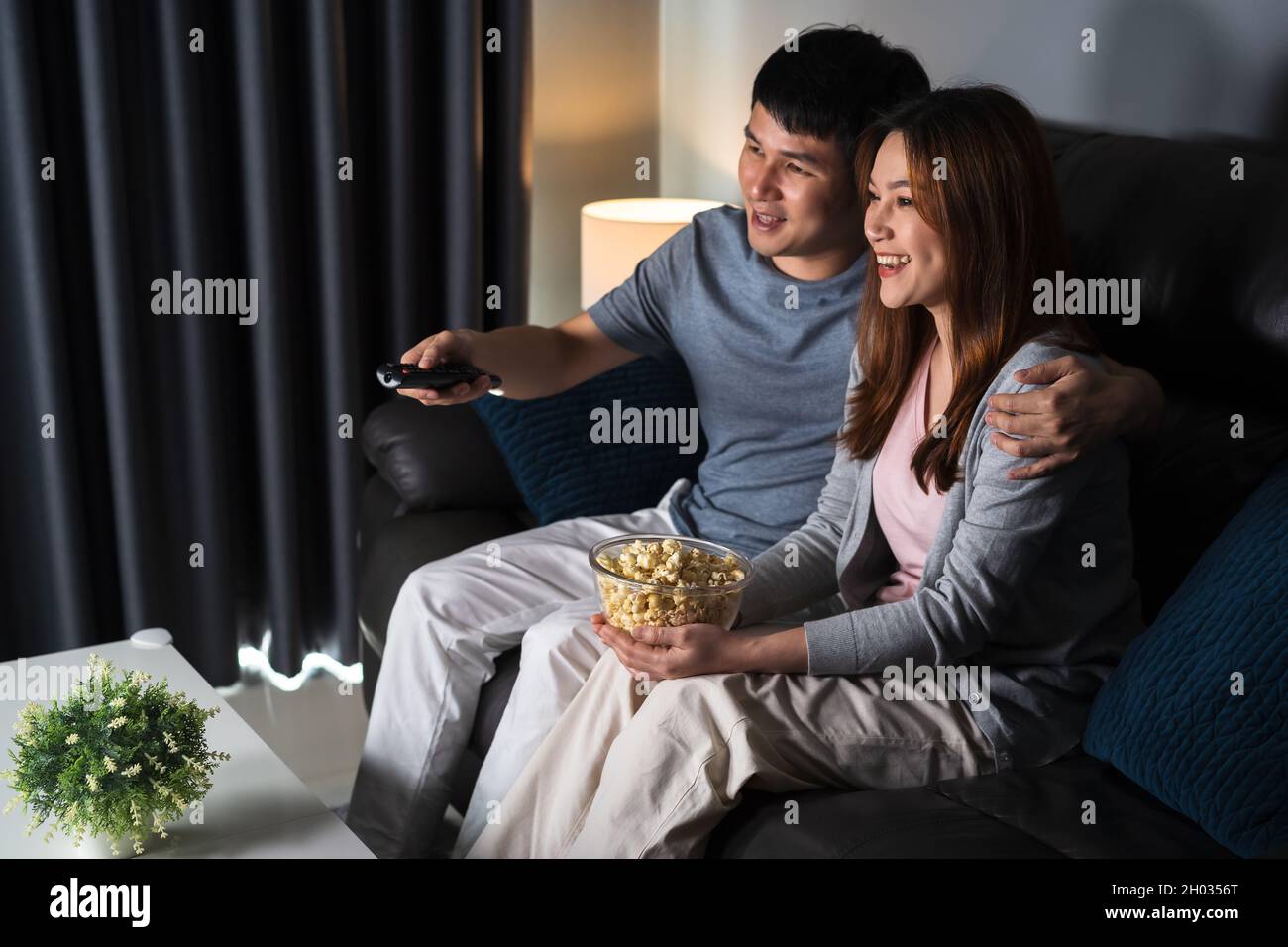 Felice coppia giovane che guarda la TV sul divano di notte Foto Stock