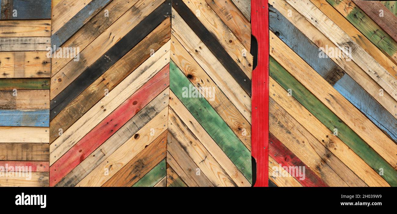 Motivi geometrici astratti altamente unici realizzati con palette di legno tagliate riciclate disposte a strisce diagonali. Tavole a ciclo superiore multicolore Foto Stock