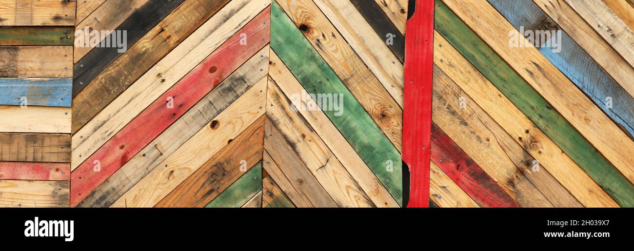 Motivi geometrici astratti altamente unici realizzati con palette di legno tagliate riciclate disposte a strisce diagonali. Tavole a ciclo superiore multicolore Foto Stock