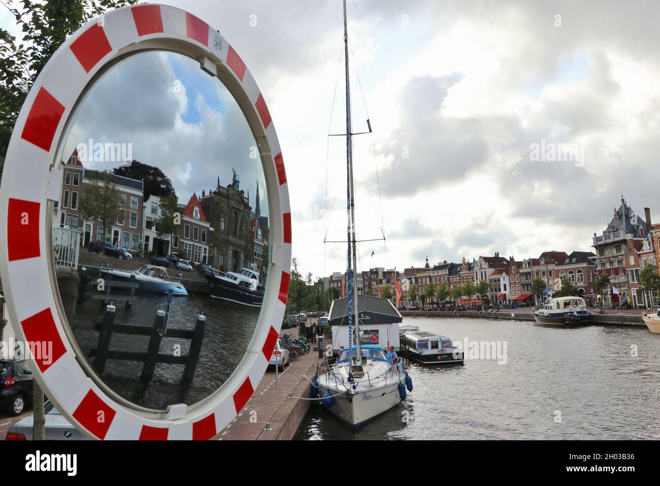Vista sul fiume Spaarne con barche e museo Teylers riflesso nello specchio di strada nel centro storico di Haarlem, Paesi Bassi, agosto 2021 Foto Stock
