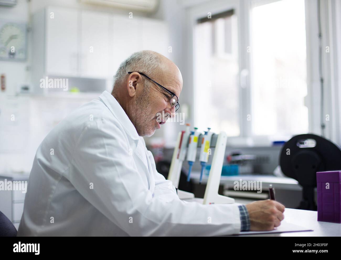 Uomo maturo biologo scrivere note sulla ricerca in laboratorio Foto Stock