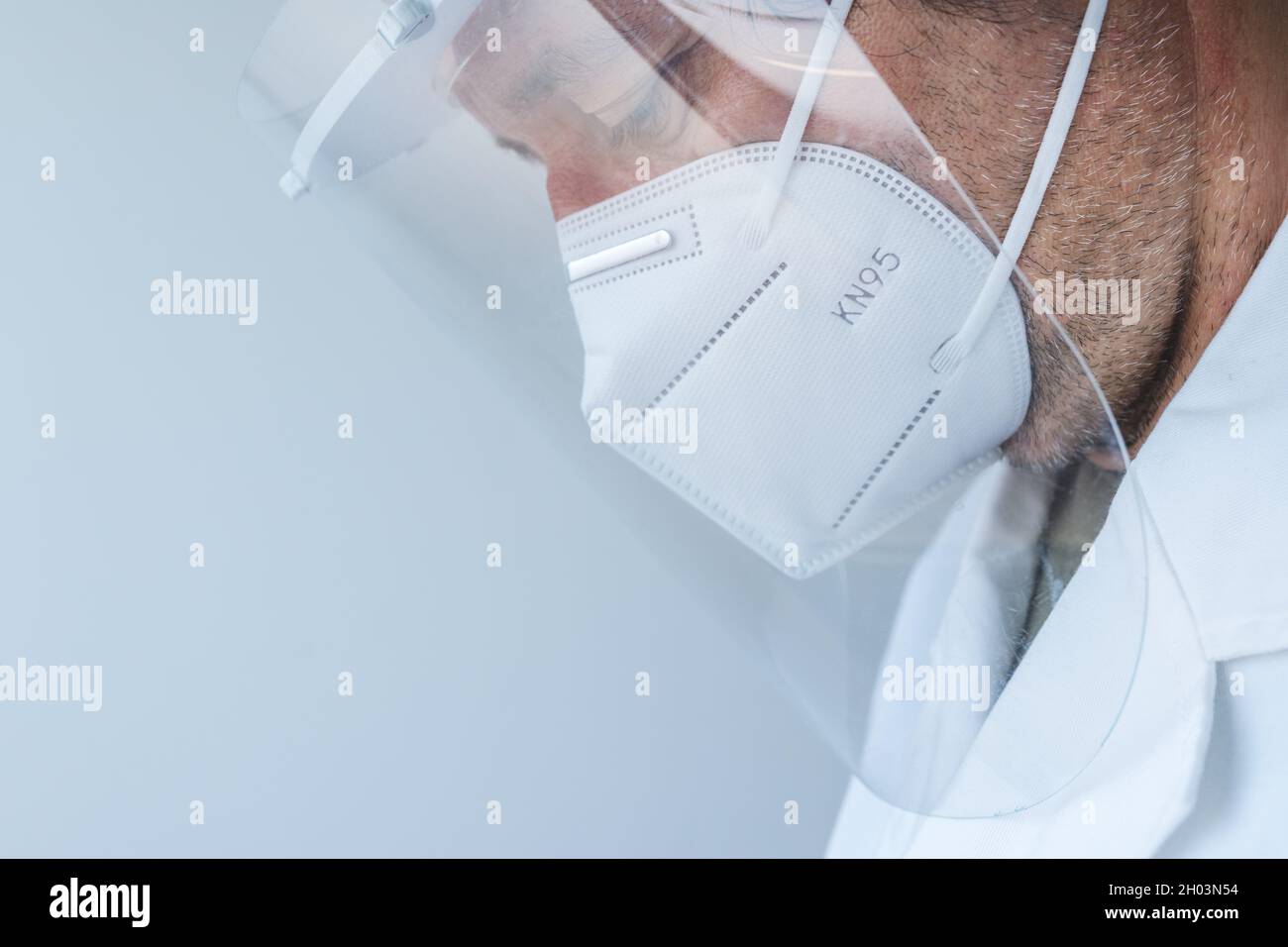 Medico professionista che indossa visiera e maschera respiratoria KN95 durante le pandemie di Covid-19, triste e medico stanco in ospedale Foto Stock