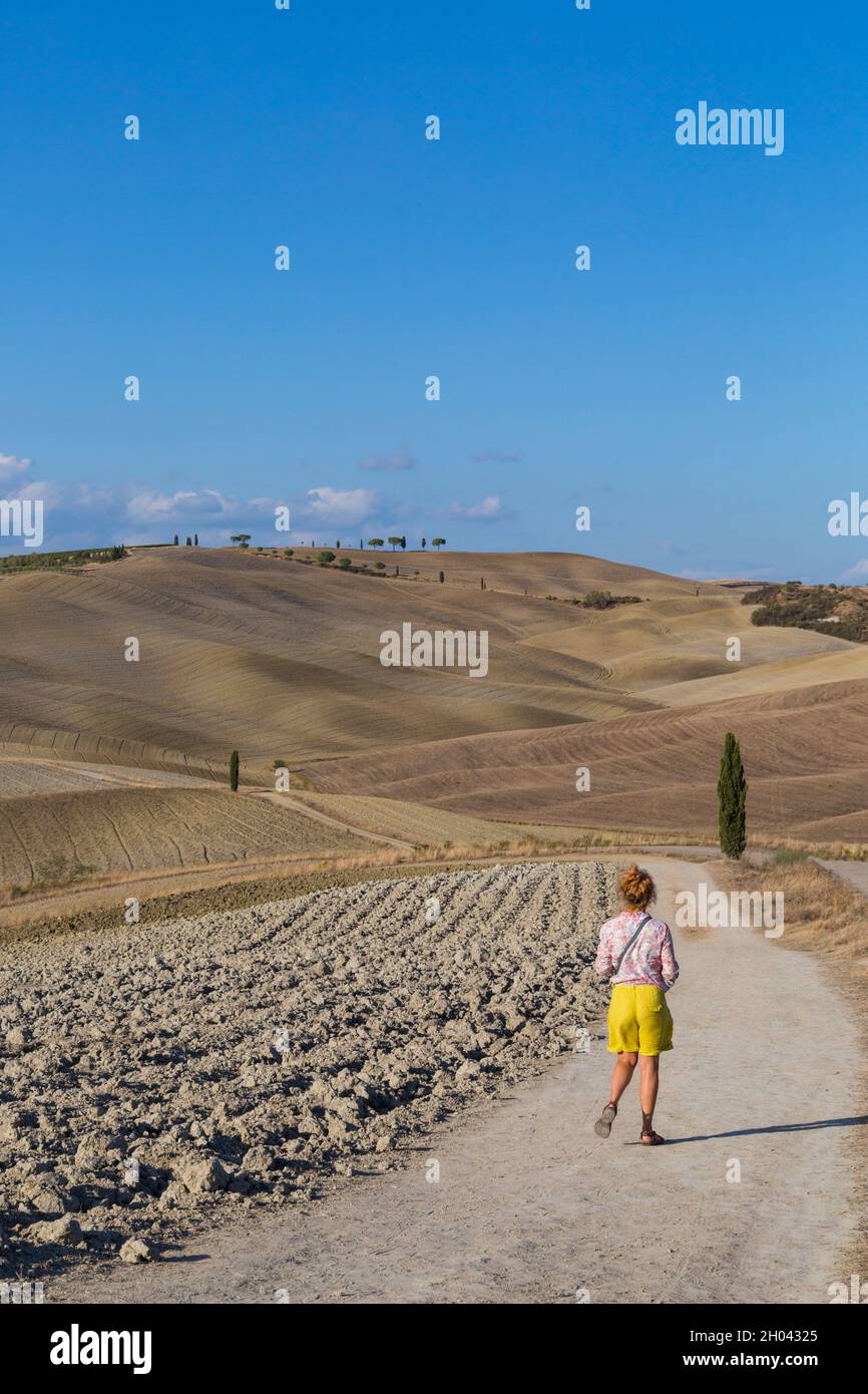 I visitatori camminano lungo il sentiero nella campagna di San Quirico d'Orcia, nei pressi di Pienza, Toscana, Italia in autunno, settembre Foto Stock