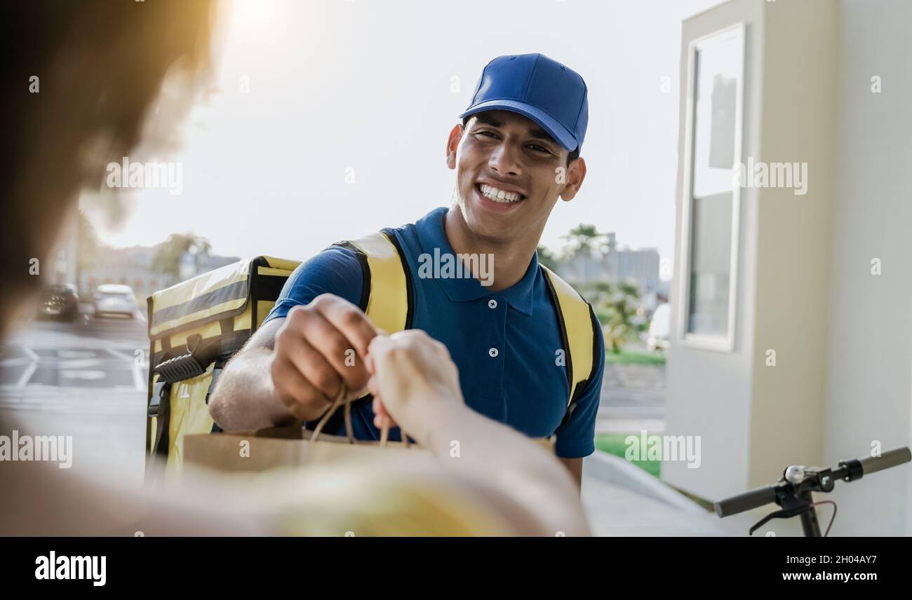 Personale di consegna ispanico che consegna fast food con scooter elettrico - fornire il servizio clienti Foto Stock