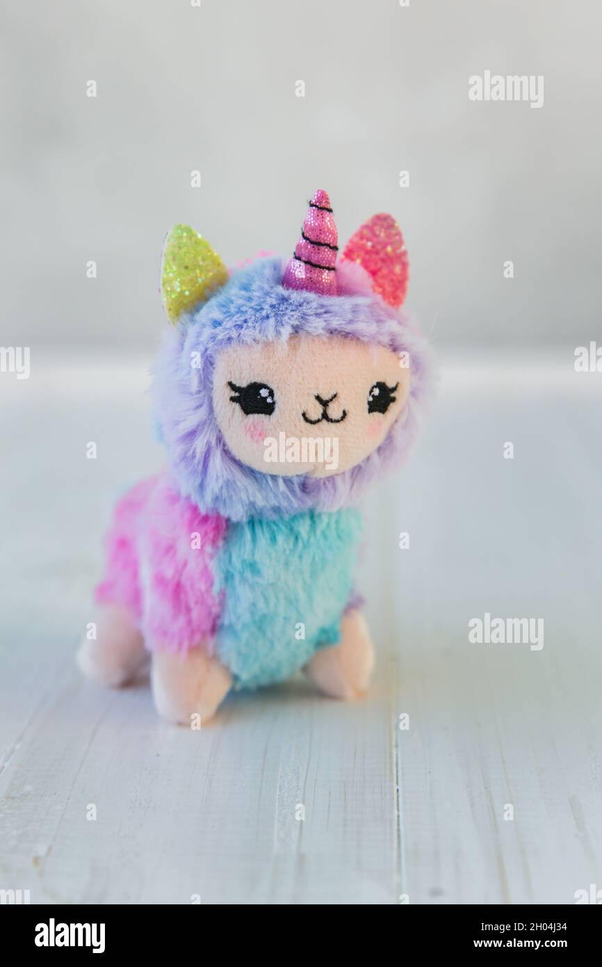 Unicorno a lama colorata su sfondo bianco in legno. Famoso e popolare giocattolo per bambini. Foto Stock