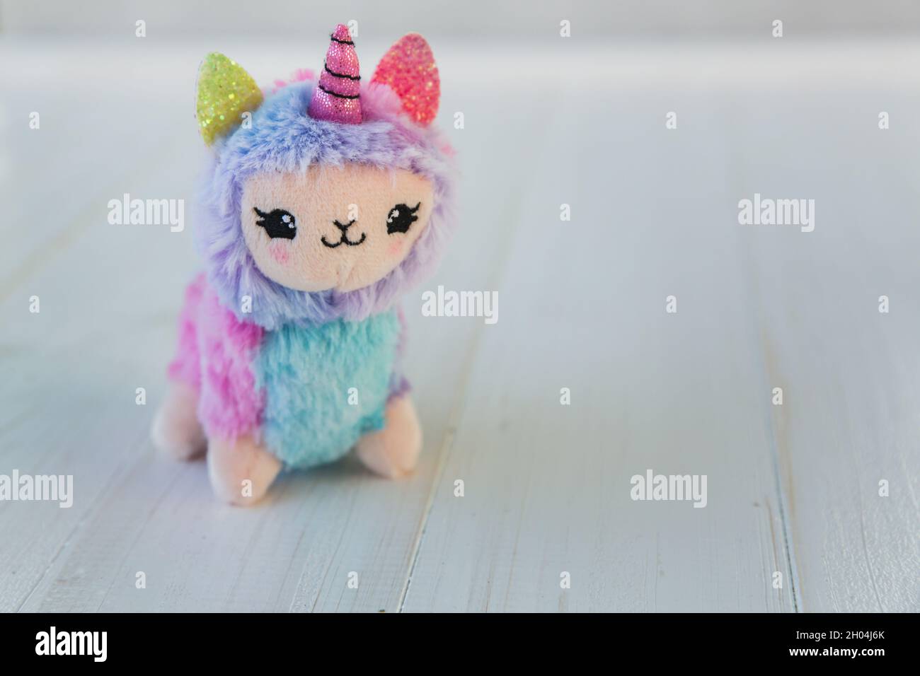 Unicorno a lama colorata su sfondo bianco in legno. Famoso e popolare giocattolo per bambini. Foto Stock