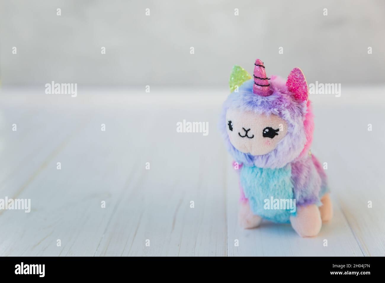 Unicorno a lama colorata su sfondo bianco in legno. Famoso e popolare giocattolo per bambini. Foto Stock