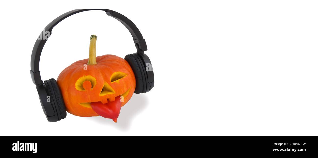 Zucca di Halloween con cuffie per musica su sfondo bianco. Lingua fuori dal pepe. Lanterna jack dalla zucca succosa Foto Stock