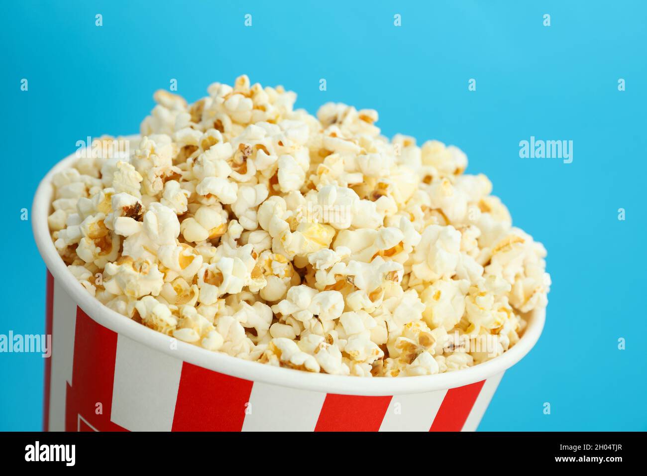 Tazza di carta con popcorn su sfondo blu. Foto Stock