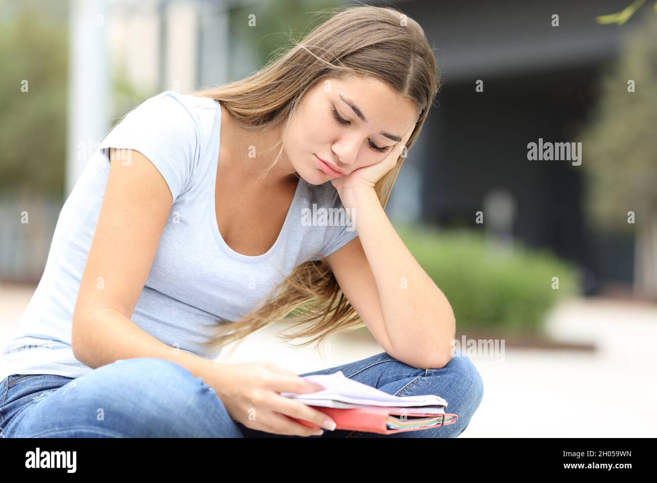 Studente frustrato cercando di imparare a leggere le note seduti per strada Foto Stock