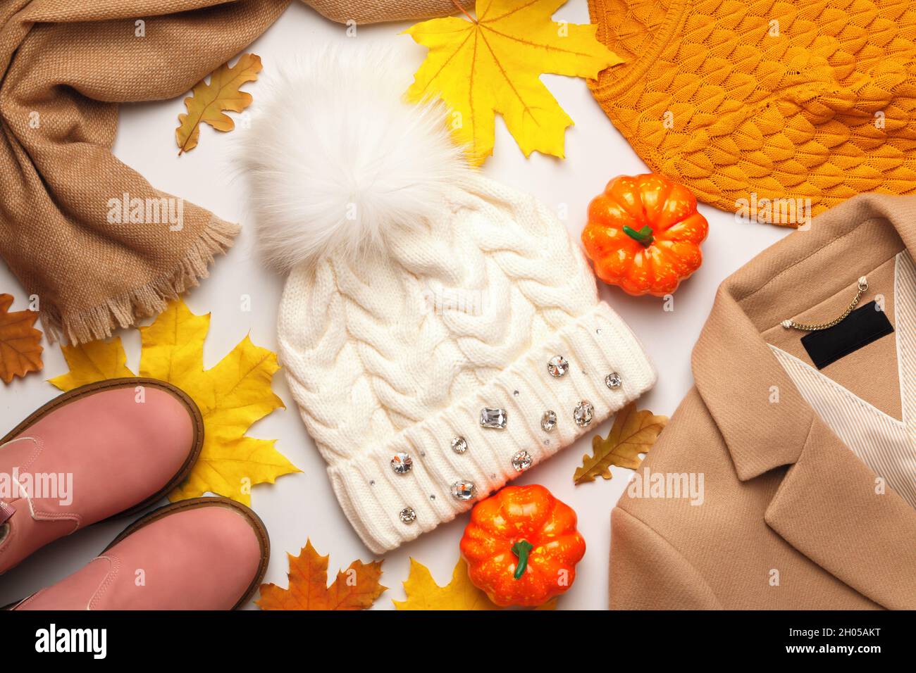 Una serie di caldi vestiti autunno-inverno con foglie e zucche cadute su sfondo bianco. Vista dall'alto Flat Lay Foto Stock