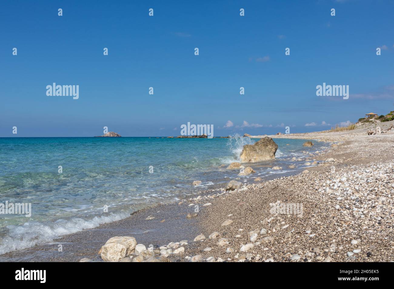 L'onda si spruzza sulla spiaggia di ciottoli bianchi da vicino con acque cristalline sulla costa dell'isola di Lefkada in Grecia. Vacanze estive natura viaggio a Ionian Sea Foto Stock
