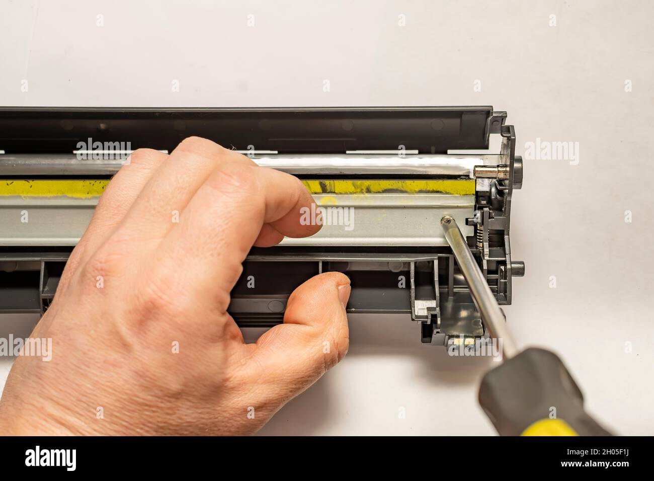 un pezzo di ricambio, una spatola in una cartuccia laser smontata è avvitata con un cacciavite a mano di un master del centro di assistenza Foto Stock