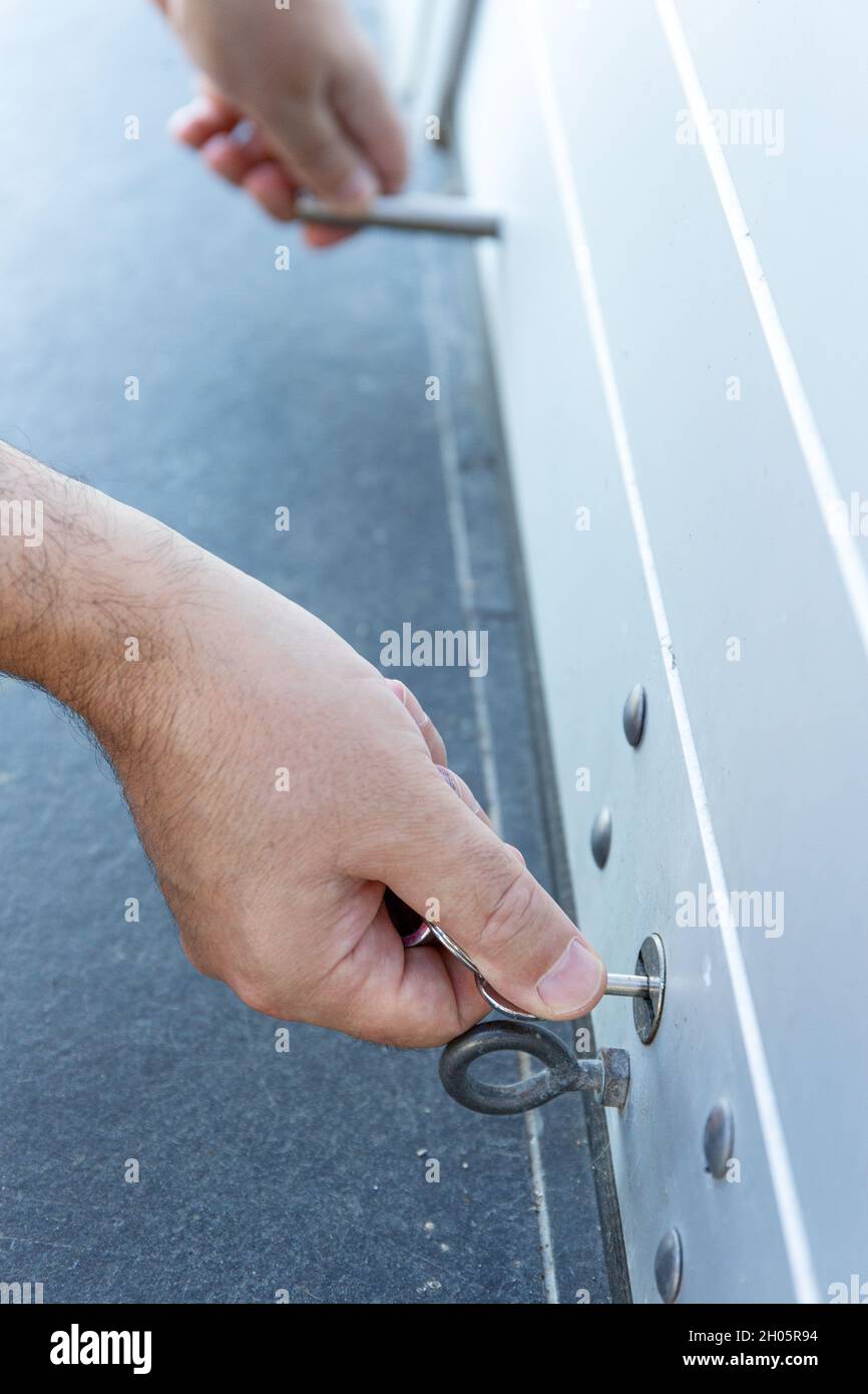 Primo piano di una mano con una chiave che chiude lo sportello dell'otturatore a rullo di un negozio. Concetto di chiusura Foto Stock
