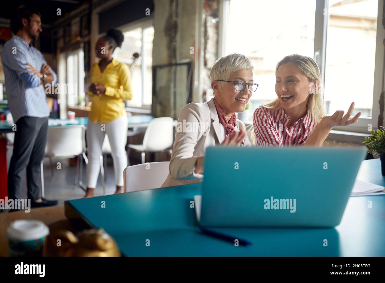 Le colleghi femminili commentano e apprezzano i contenuti dei notebook al lavoro in un'atmosfera amichevole in ufficio Foto Stock