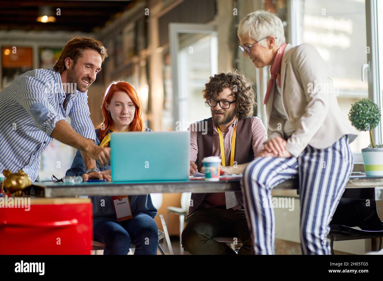 boss soddisfatti che mostrano ai giovani dipendenti adulti nuove idee di business su un notebook, sorridendo, Foto Stock