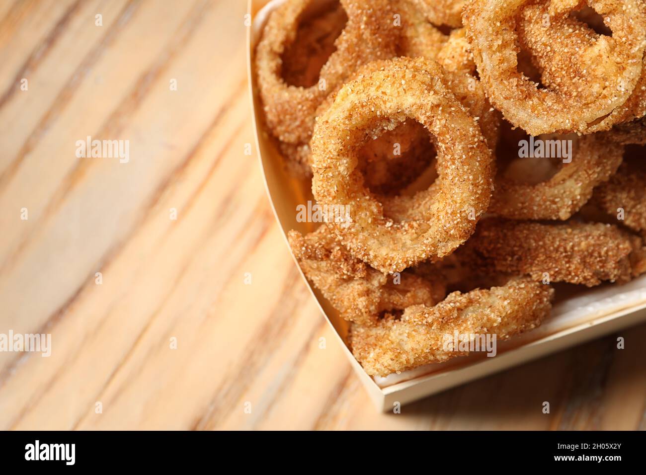 Scatola di cartone con anelli di cipolla fritta croccante su sfondo di  legno, primo piano. Spazio per il testo Foto stock - Alamy