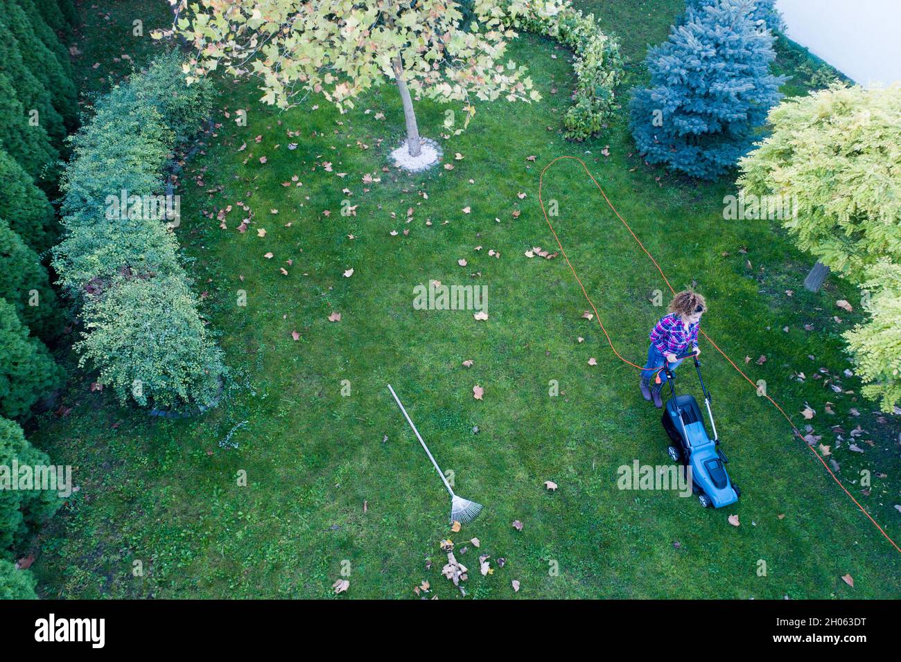 Vista aerea della ragazza falciando prato in cortile sparare dal drone Foto Stock