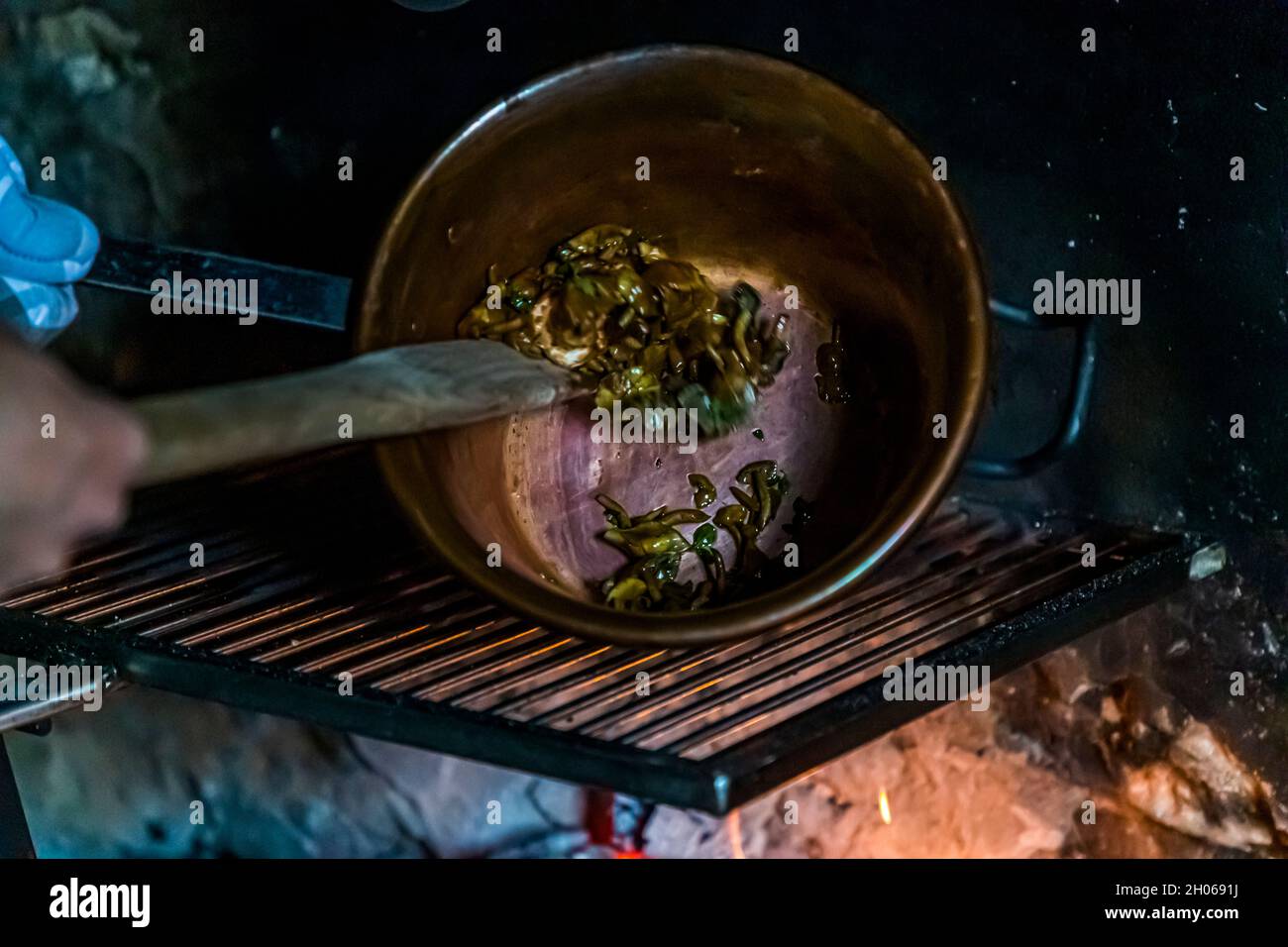 A Cerentino, i visitatori possono soggiornare nella storica casa patrizia Cà Vegia, finemente ristrutturata, con mobili secolari ma senza elettricità. Con un po' di grasso, i funghi autolarati vengono saltati sul fuoco, Circolo della Rovana, Svizzera Foto Stock