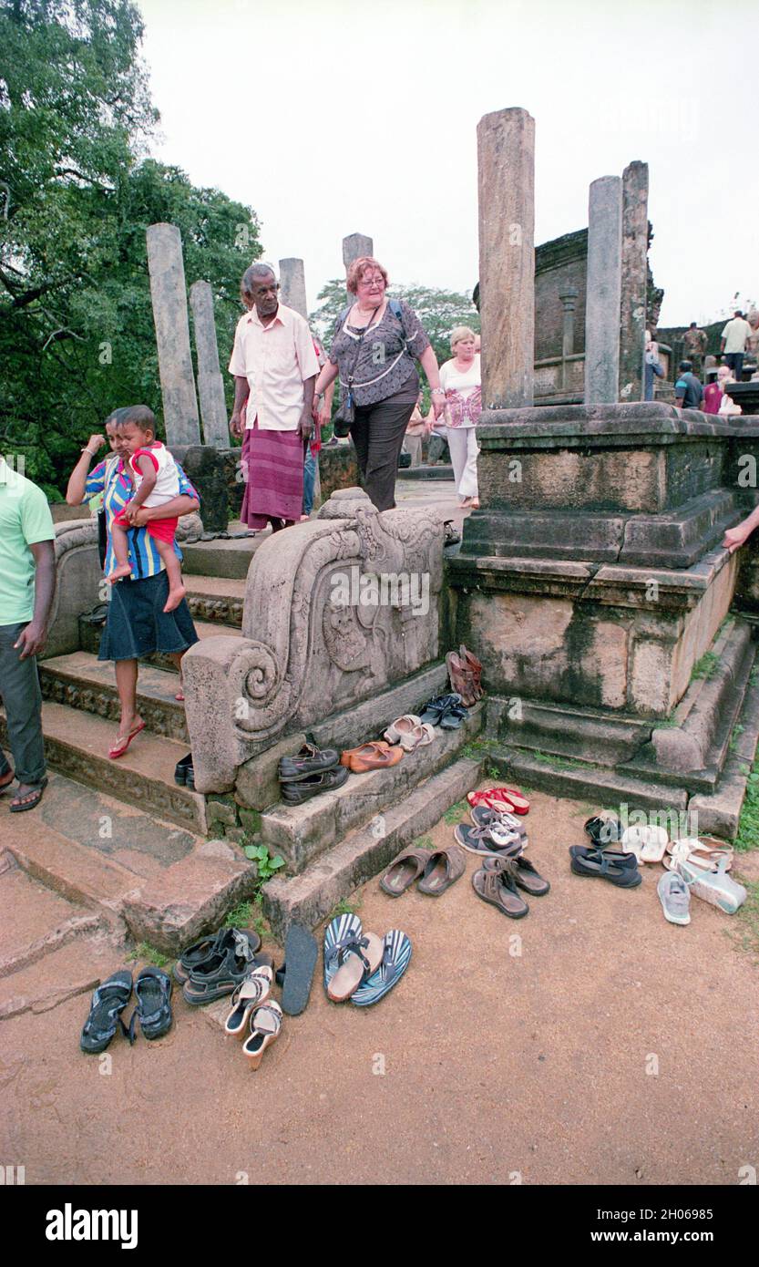 Il turista DELLO SRI LANKA lascia un tempio buddista per raccogliere le scarpe a Polonnaruwa Foto Stock