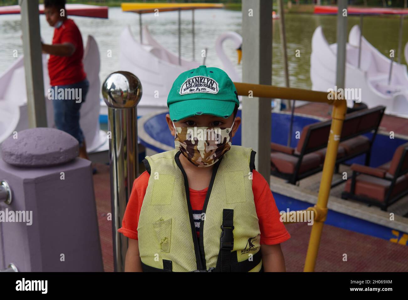 Un bambino che indossa un giubbotto salvagente di sicurezza prima di essere rilasciato per giocare a pedalò per la famiglia al City Lake Park Kuantan Malesia. Foto Stock